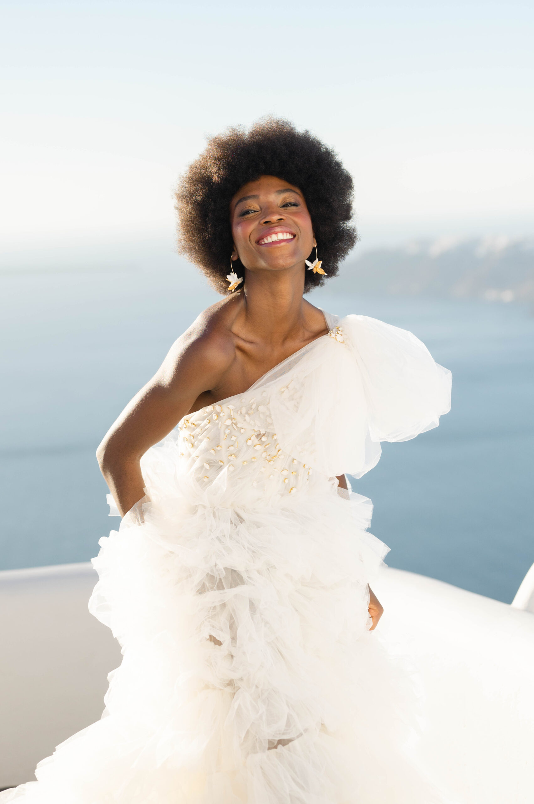A beautiful Bride smiling in a couture wedding dress at Golden Hour in Santorini, Greece